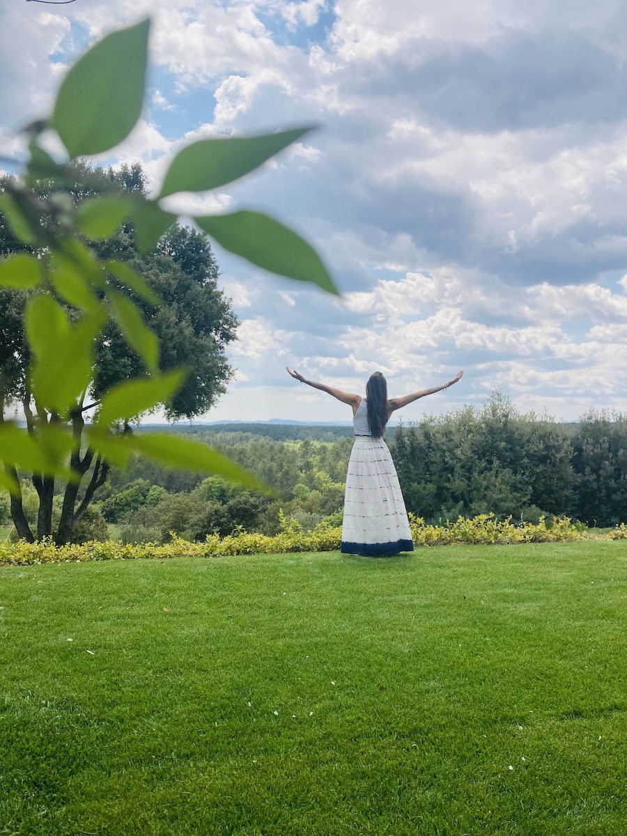 jeune femme de dos dans une prairie les bras écartés